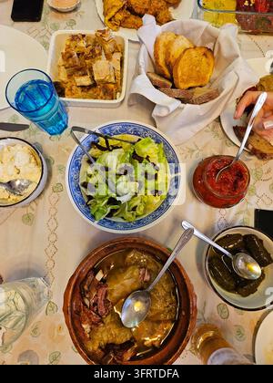 Table is set with a variety of food, including a salad, bread, and a bowl of soup. There are also several cups and spoons on the table. The table is s Stock Photo