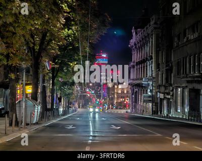 City street at night with a tall building in the background. The street is empty and the lights are on in Belgrade Stock Photo