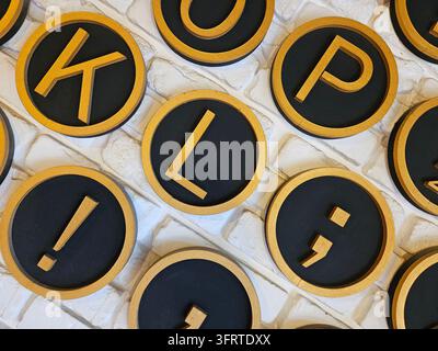 Collection of alphabetical letter coasters made of wood and gold. The letters are arranged in a circle and are of varying sizes. The coasters are placed on a white background Stock Photo