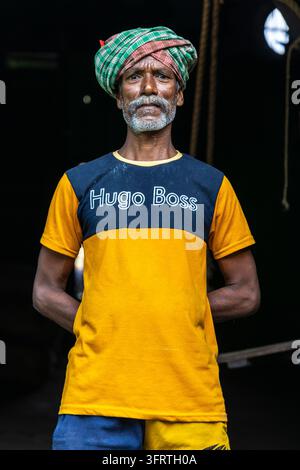 Frontal portrait of a man with his hands behind his back in a dark ...