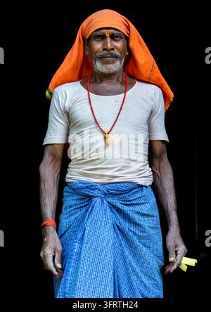 Older worker with a white mustache and a sacred mark on his forehead poses straight facing the camera wearing a white undershirt, West Bengal, Howrah, Stock Photo