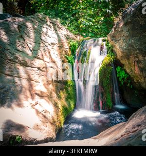 Close up of a small waterfall cascading over mossy rocks in a creek in Richtis Gorge, Crete, Greece Stock Photo