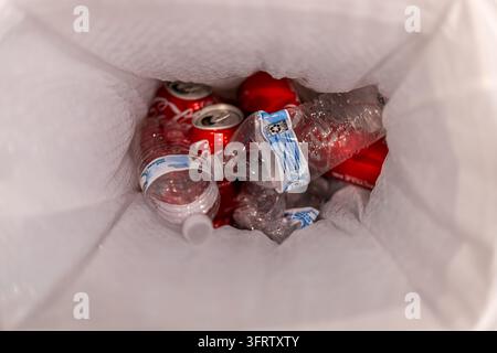 Los Angeles, California, USA - October 12, 2026: Crushed plastic water bottles and red aluminum soda cans collected inside white plastic bag, Stock Photo