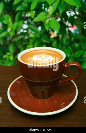 Cozy cappuccino with Halloween Latte Art on blurry garden background Stock Photo