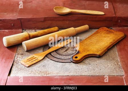 Wooden kitchen utensils on the stove. Wooden cutting board, rolling pins, spoons. Stock Photo