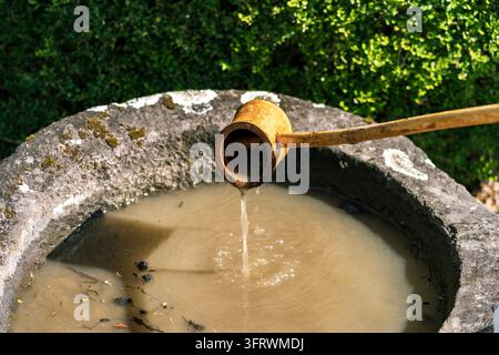 Traditional Japanese Tsukubai Stone Water Basin and Bamboo Ladle for Purification Stock Photo