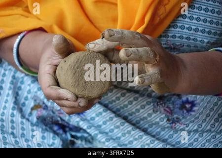 Close-up of an Indian woman's hands molding and shaping wet raw clay to make traditional earthenware in a rural pottery workshop, India Stock Photo