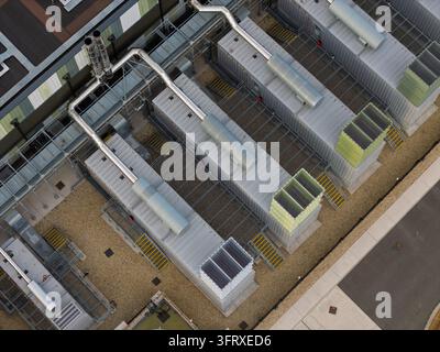 Large cooling units and ventilation infrastructure are arranged on the roof of a secure Data Center building to support server operations and maintain Stock Photo