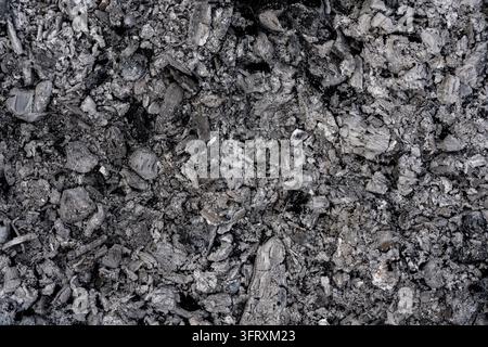 Wood ash and charcoal texture abstract background. Burnt wood ash mixed with black charcoal pieces. Full frame dark grey backdrop for fireplace, campf Stock Photo