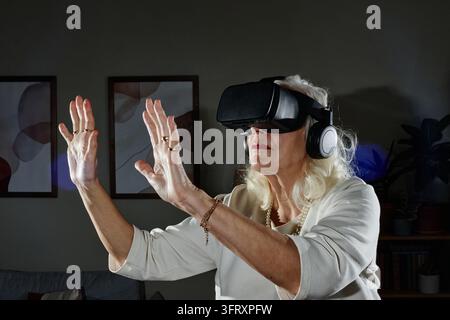 Senior Woman Using Virtual Reality Headset for Interactive Simulation Stock Photo