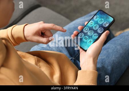 Man using astrology app on his smartphone indoors, closeup Stock Photo