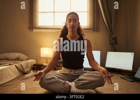 Biracial Woman Meditating on Floor Practicing Mindfulness at Home Stock Photo