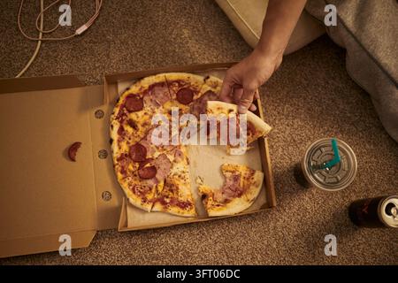 Man Taking Slice of Delivered Pizza from Box at Home Stock Photo