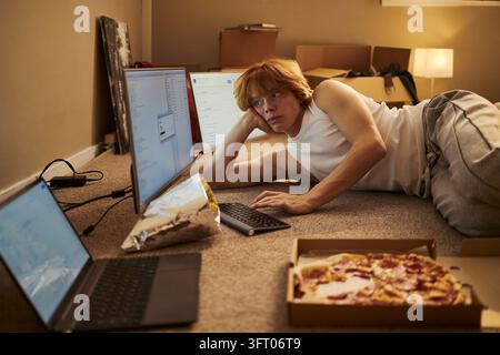 Man Lying on Floor Working with Computers in New Apartment Stock Photo
