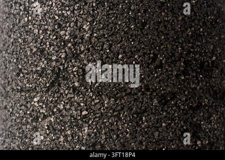 black granular activated carbon filter in full frame background, cylindrical water purification cartridge in close-up view, industrial plumbing Stock Photo