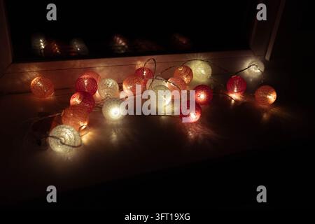 Burning Red Candle with Festive Decorative Lights in a Cozy Dark Setting Stock Photo