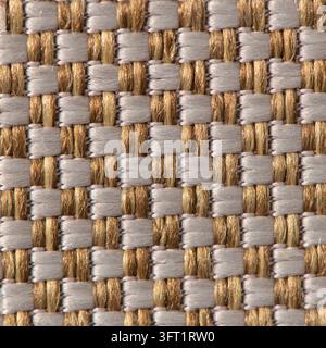 A close-up of a woven textile fabric featuring an intricate geometric grid pattern in metallic gold and silver tones, creating a sleek and elegant sur Stock Photo