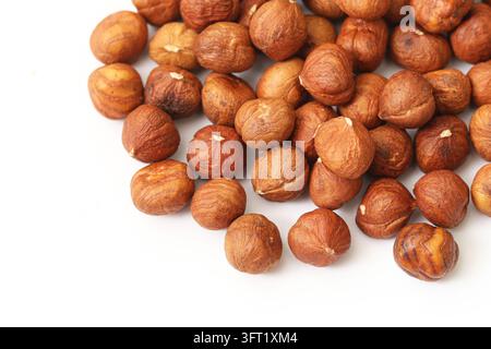 Closeup of whole brown hazelnuts scattered on white surface. Nut texture background for healthy snacks, natural food, plant protein and autumn harvest Stock Photo