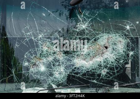 Close-up view of heavily shattered laminated safety glass windscreen with multiple impact points, spiderweb crack networks and crushed central zone re Stock Photo