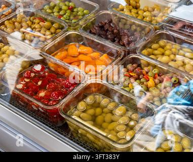 Clear plastic trays filled with marinated green and black olives, cheese-stuffed red cherry peppers, orange peppers and sun-dried tomatoes Stock Photo