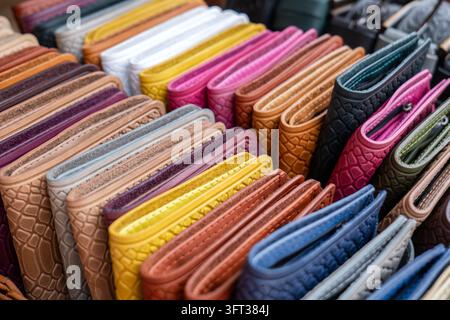Rows of folded leather wallets and small purses arranged side by side on a market stall, embossed with a crocodile skin pattern. The wallets stand Stock Photo