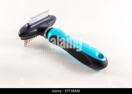 A close up studio product photograph of a modern blue and black dual sided pet grooming tool featuring a fine deshedding blade edge on one side and a Stock Photo