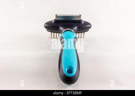 A close up studio product photograph of a modern blue and black dual sided pet grooming tool featuring a fine deshedding blade edge on one side and a Stock Photo