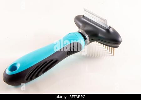 A close up studio product photograph of a modern blue and black dual sided pet grooming tool featuring a fine deshedding blade edge on one side and a Stock Photo