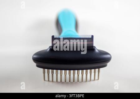A close up studio product photograph of a modern blue and black dual sided pet grooming tool featuring a fine deshedding blade edge on one side and a Stock Photo