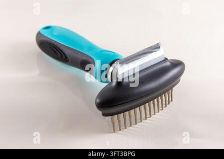 A close up studio product photograph of a modern blue and black dual sided pet grooming tool featuring a fine deshedding blade edge on one side and a Stock Photo