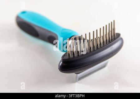 A close up studio product photograph of a modern blue and black dual sided pet grooming tool featuring a fine deshedding blade edge on one side and a Stock Photo
