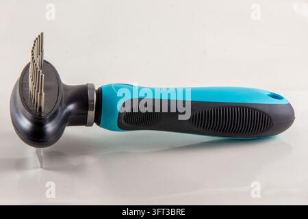 A close up studio product photograph of a modern blue and black dual sided pet grooming tool featuring a fine deshedding blade edge on one side and a Stock Photo