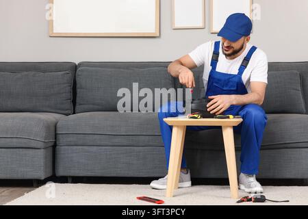 Home repair and maintenance service, handyman fixing household appliance with screwdriver in living room Stock Photo