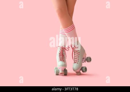 Retro nostalgia and leisure lifestyle, woman wearing vintage roller skates with striped socks on a pastel pink background Stock Photo