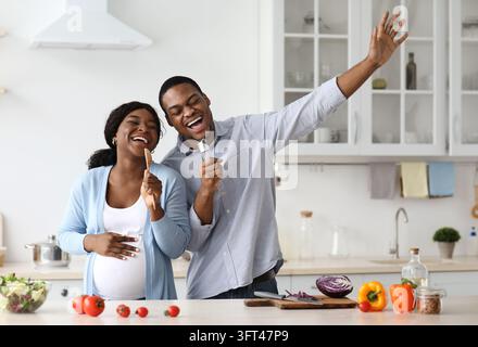 Joyful pregnant black couple having fun while cooking Stock Photo