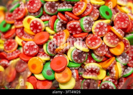 Colorful assorted gummy candies with intricate red and white patterns in a closeup view, bright green yellow orange and red chewy sweets creating a Stock Photo