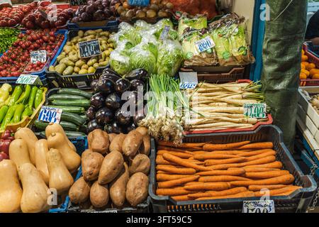 Colorful fresh vegetables and fruit fill a Budapest market stall, with handwritten price signs visible among the produce. Stock Photo