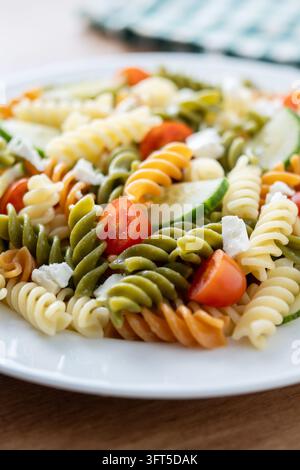 Colorful fusilli pasta salad with fresh vegetables and feta cheese on ...