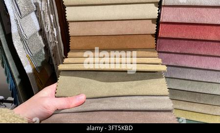 Close-up of customer hand selecting colorful upholstery fabric samples in different shades and textures at furniture showroom Stock Photo
