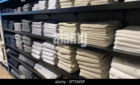 Neatly folded bath towels in gray, beige and white colors stacked on black shelves at home textile store Stock Photo