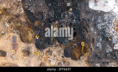 Aerial view of multiple yellow excavators working on a muddy construction site in India. Stock Photo