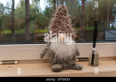 Decorative toy gnome and reed diffuser on windowsill Stock Photo