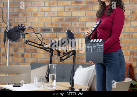 African American woman holding clapperboard in studio with microphones and smartphone, copy space Stock Photo