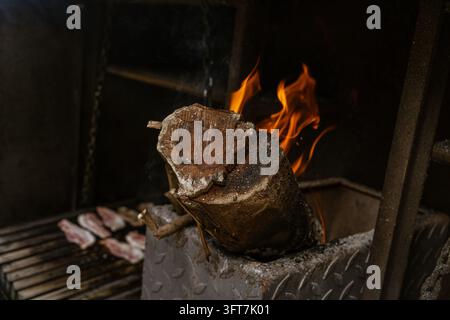 Burning Log in a Barbecue with Glowing Embers and Flames Stock Photo