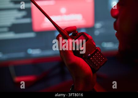 Black Man Holding Walkie-talkie in Front of Cyber Security Monitor Stock Photo