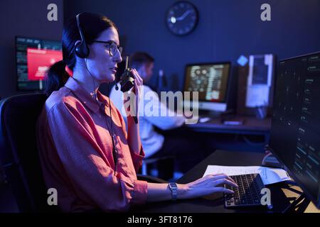 Woman Using Walkie Talkie at Cybersecurity Operations Center Stock Photo