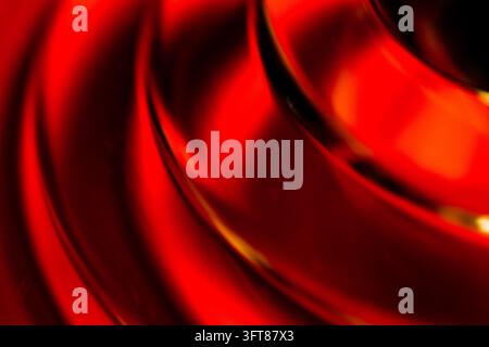 Abstract image featuring a closeup of colorful glass, captured with a high magnification macro lens. Vibrant red and orange hues create dynamic, fluid Stock Photo