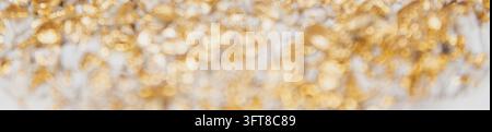 Full frame defocused view of golden glitter bokeh lights on white background for luxury holiday celebration banner stock photo layout. Stock Photo