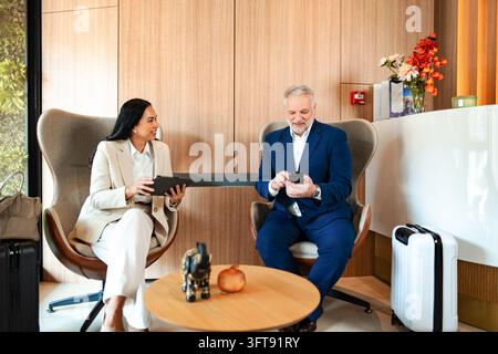 Business travelers waiting in modern hotel lobby area Stock Photo