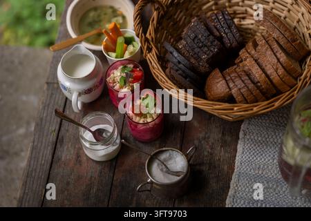 Traditional potato salad and dark rye bread served on a rustic wooden table, accompanied by creamy salad dressing, fresh vegetable sticks Stock Photo